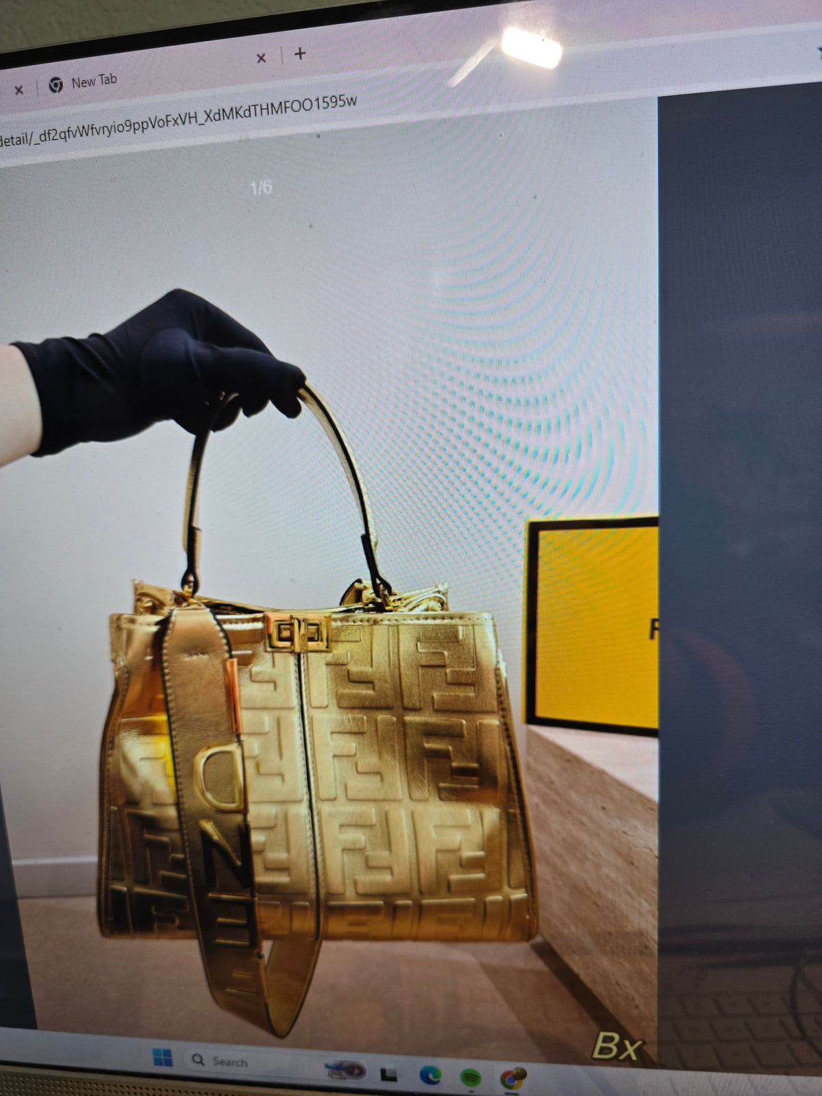 A Gold Fendi handbag wih the brands Logo FF.
The handbag s shown in mirror reflection on a computer screen
